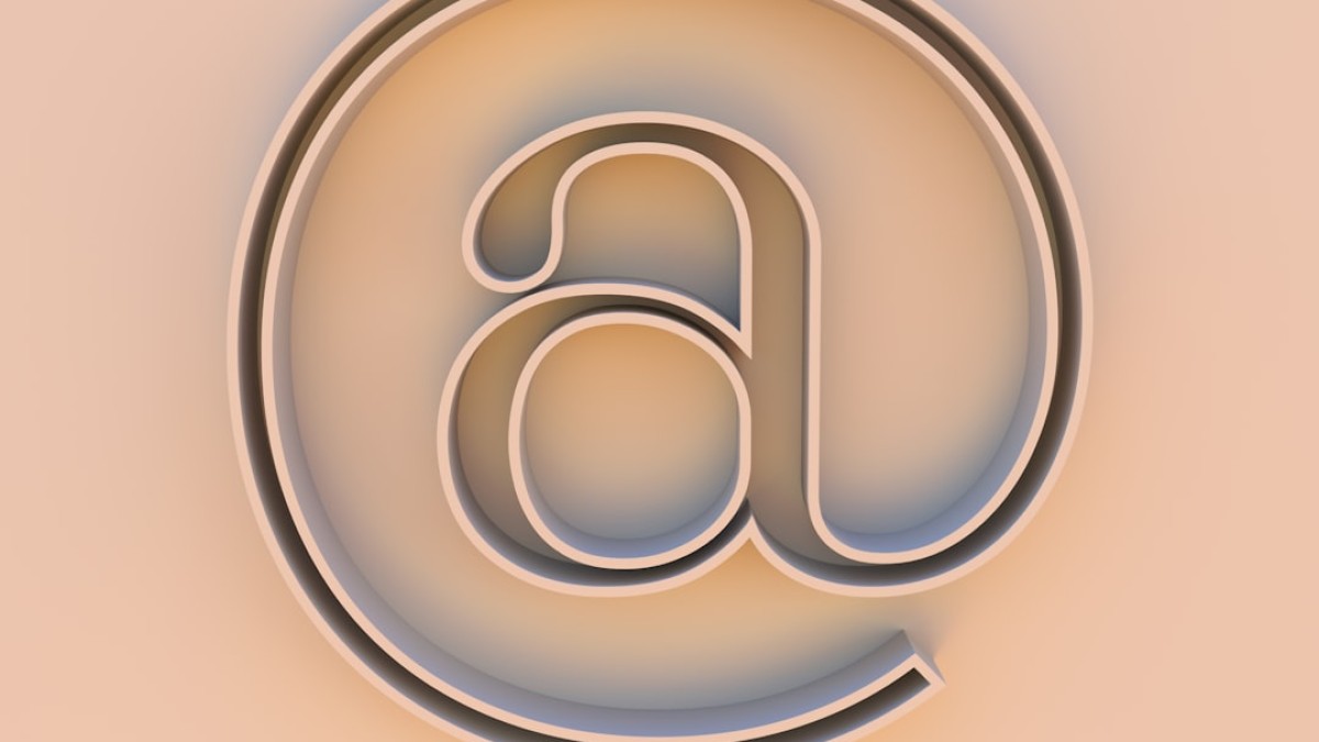 An "at" symbol on a beige background.