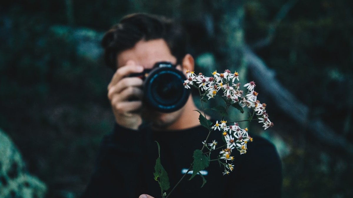 man in black crew neck shirt holding black dslr camera