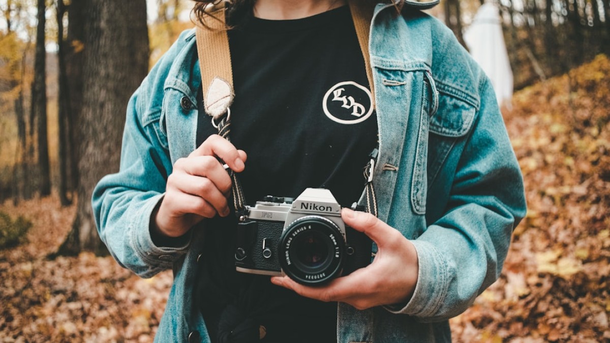 woman holding gray Nikon camera