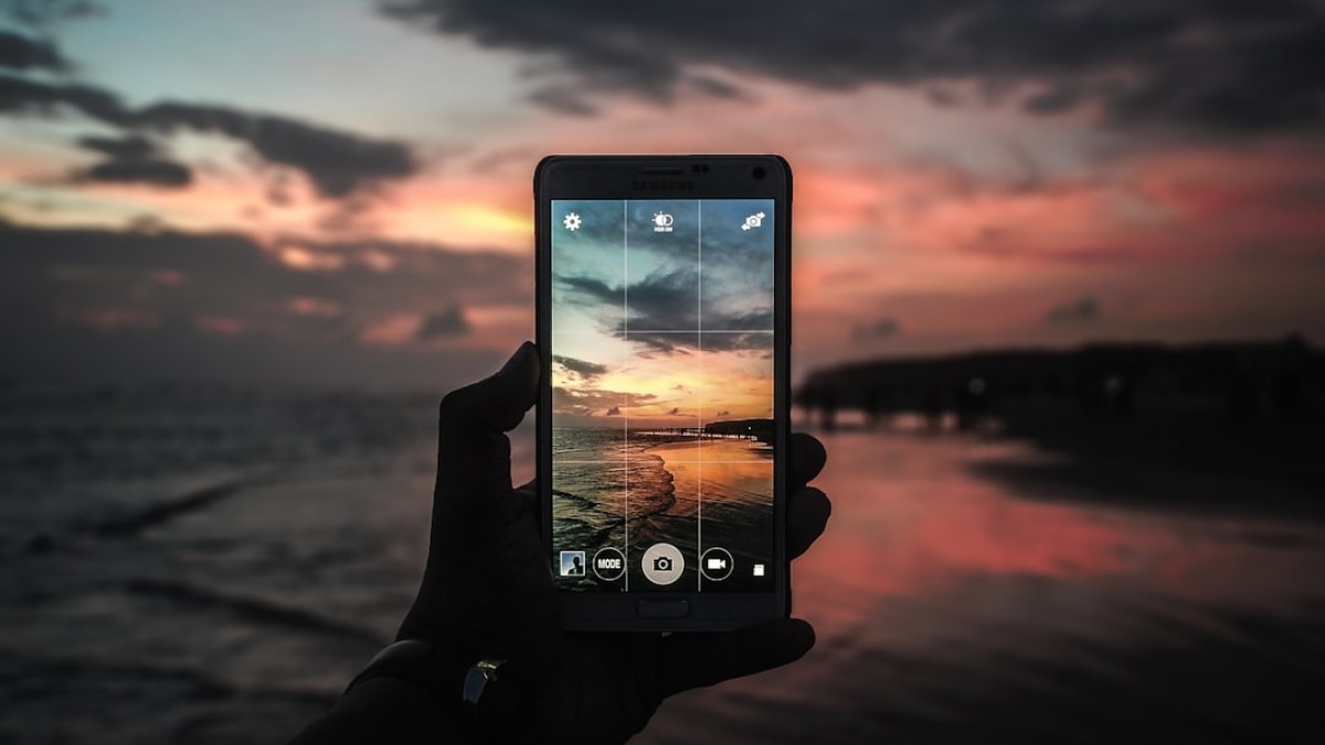 black smartphone taking photo of golden hour horizon