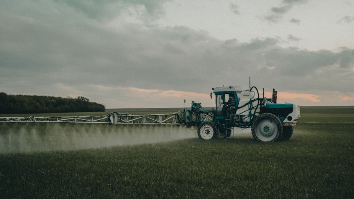 green tractor on green grass field under cloudy sky during daytime