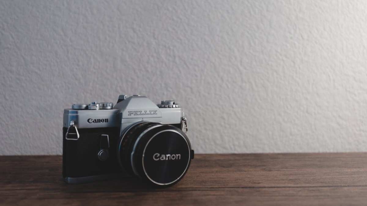silver and black Canon Pellix SLR camera on brown surface