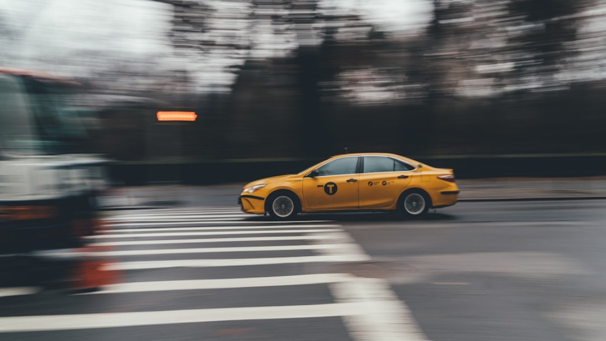 yellow taxi crosses pedestrian lane