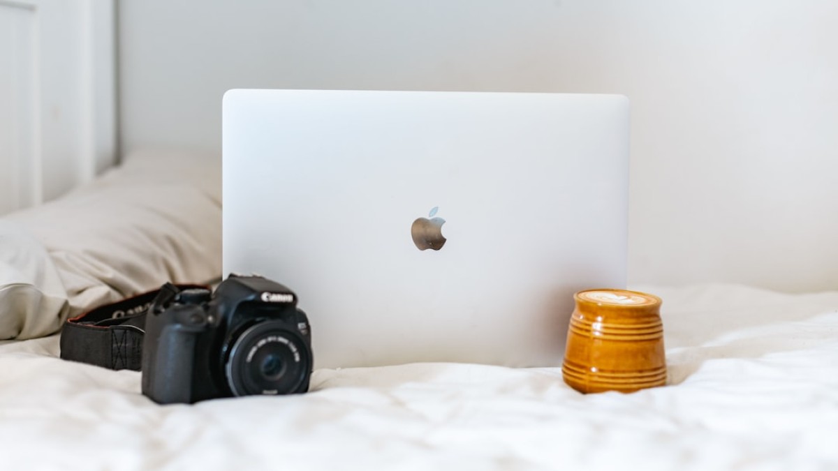 black nikon dslr camera beside silver macbook